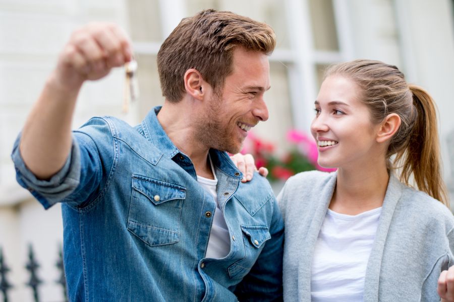 A young couple holding keys to their new house from a 15 year mortgage financed through Chris Lamm