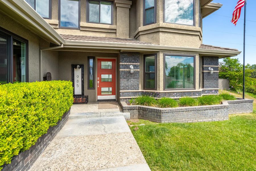 The front door of a home in redding with bushes lining the sidewalk and an American flag in the background