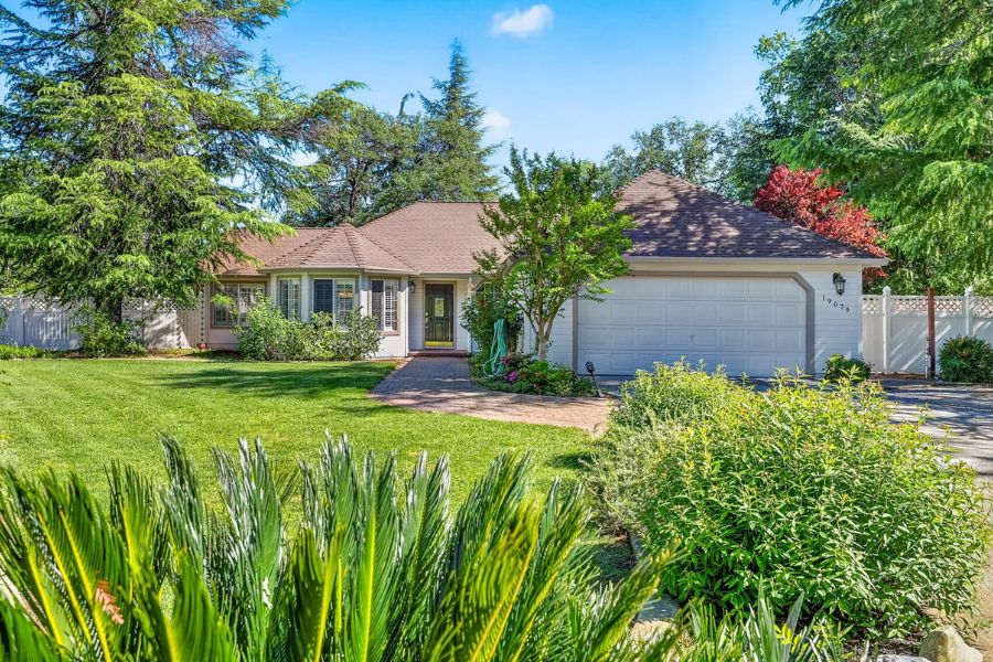 A home in Redding CA with a lush front lawn surrounded by trees